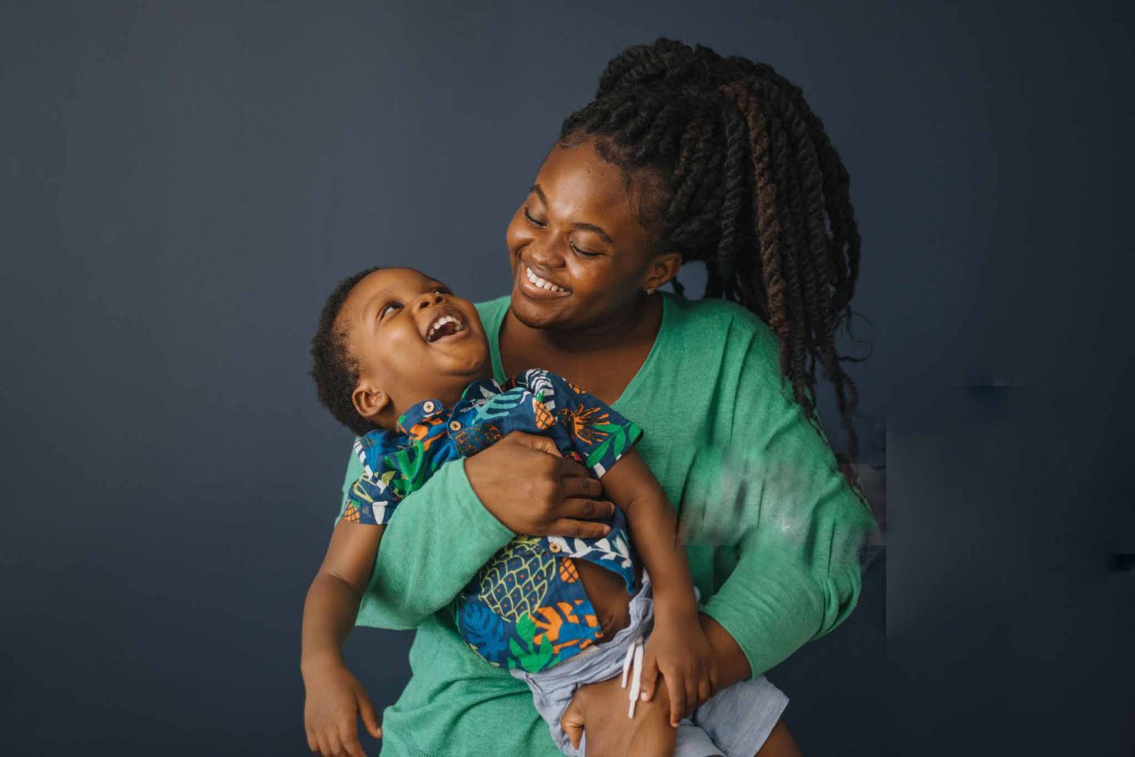 mother playing with her son studio shot on blue background